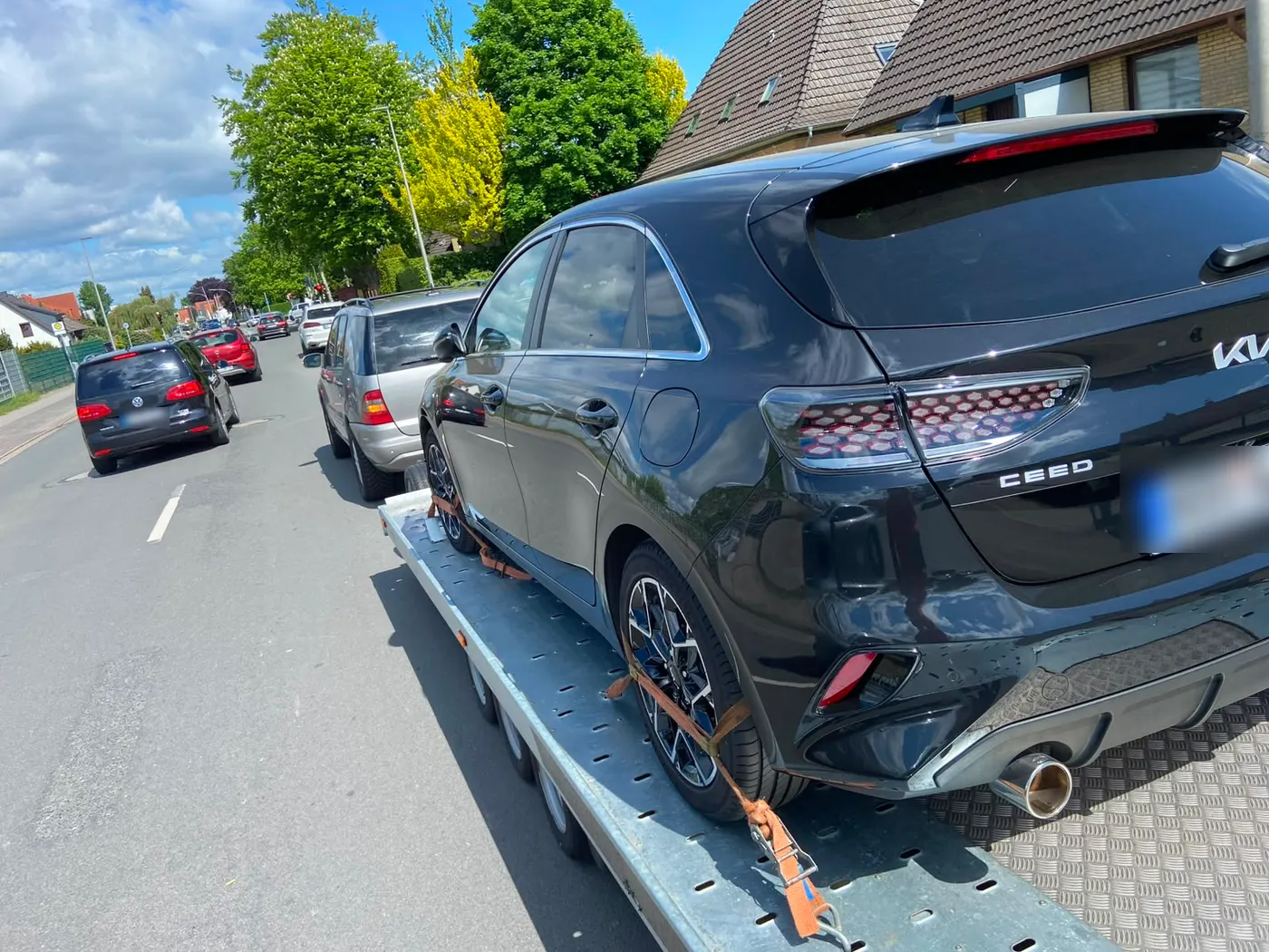 Kia auf dem Autotransportanhänger, Abholung in einer Wohnstraße