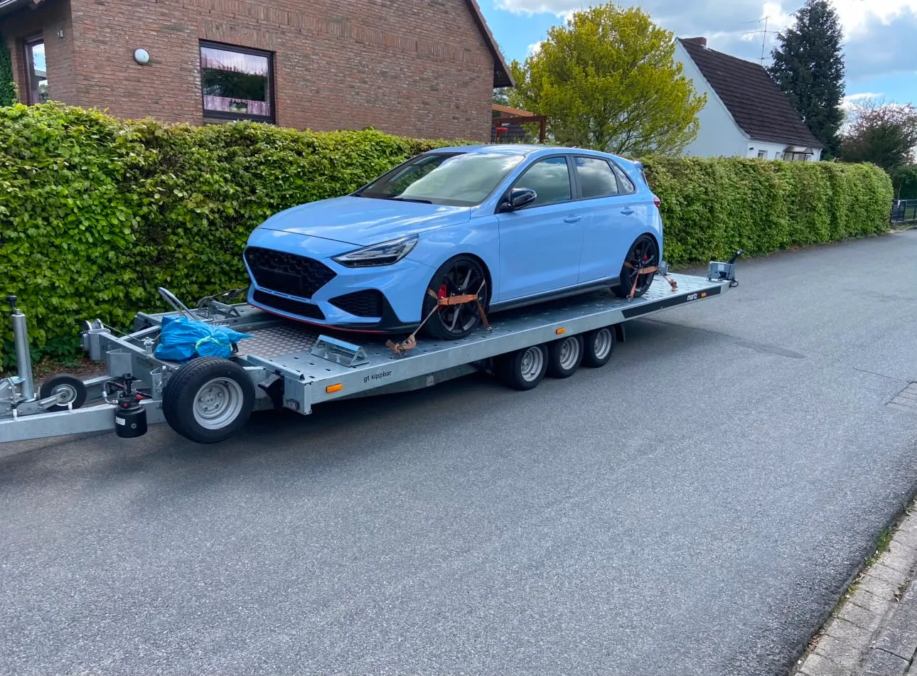 Tiefergelegter Sportwagen flach aufgeladen auf dem Kipp-Anhänger