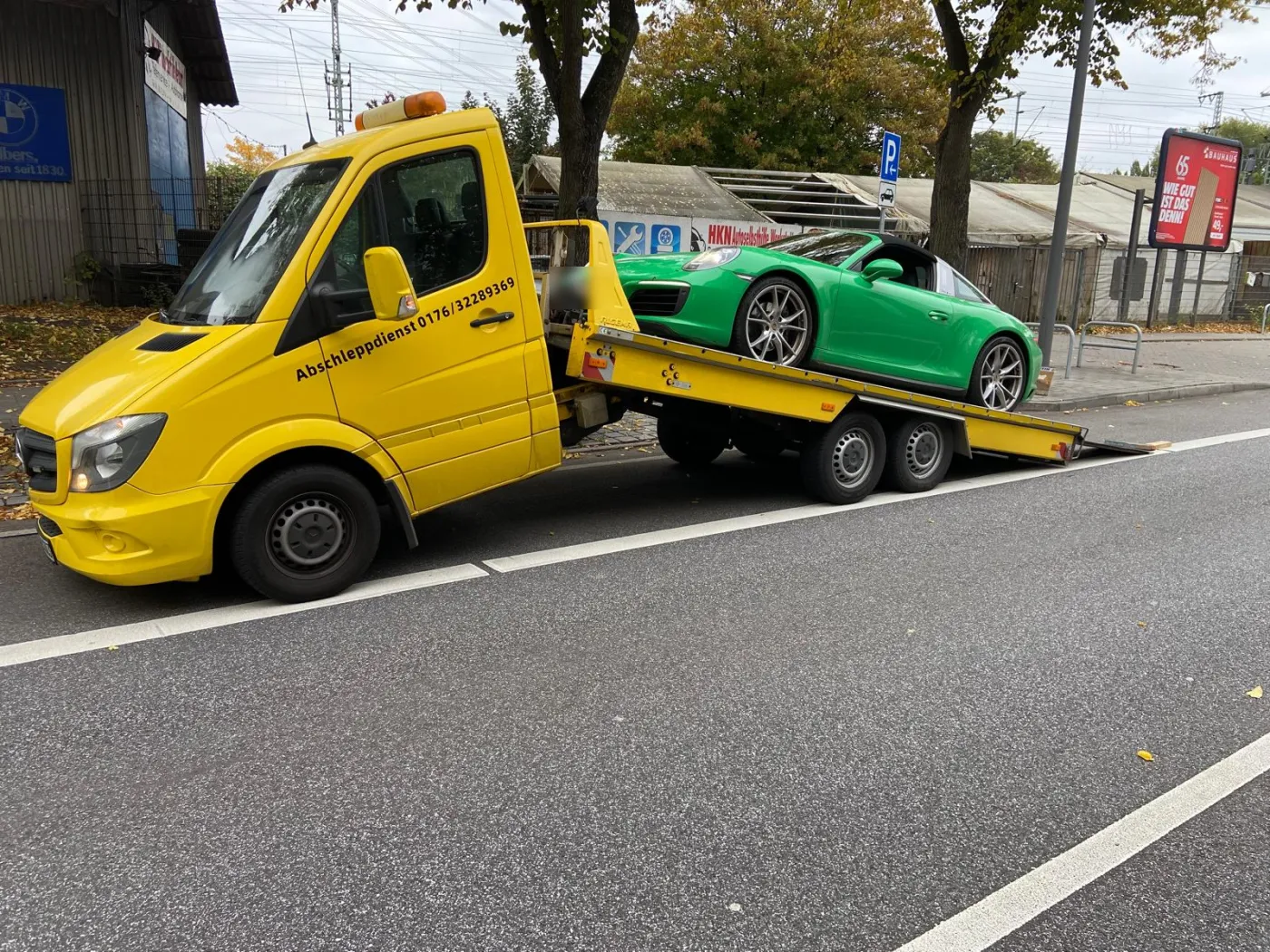 Grüner Porsche auf der Plattform des gelben Abschleppwagens